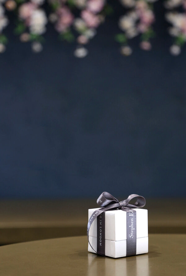 A Stephen Einhorn gift box on a bronze counter. In the background the wall is dark blue with flowers.